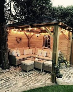 an outdoor living area with couches and lights on the roof, surrounded by brick pavers