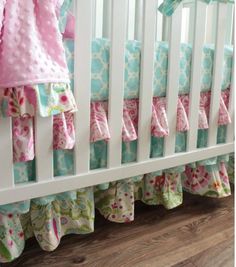 a white crib with pink and blue bedding on the bottom row, and green trim around the edges