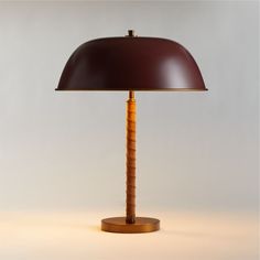 a lamp with a wooden base and a brown shade on the top is sitting on a white surface