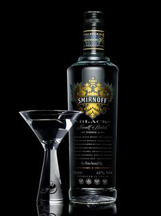 a bottle of smirnoff next to a martini glass on a black background