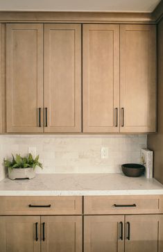 a kitchen with wooden cabinets and white marble counter tops