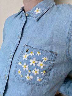 a woman wearing a denim shirt with daisies on it