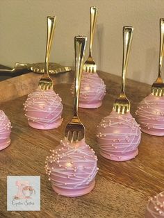 there are many pink desserts with gold forks on top of each one, all decorated in different designs