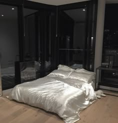 a large bed sitting in a bedroom next to a tall glass window with city lights on it