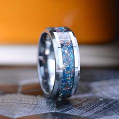 a wedding band with blue and white opal inlays is shown on top of a table