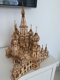 a wooden model of a castle with towers and spires is on a white table