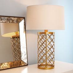 a lamp sitting on top of a white table next to a mirror and a light