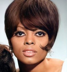 a close up of a woman with short hair and bangs on her head, looking at the camera