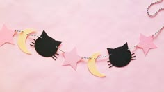 a black cat sitting on top of a moon and stars garland with pink and yellow paper