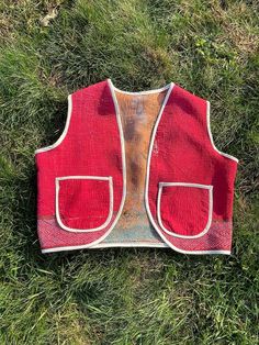 a red vest laying on top of green grass