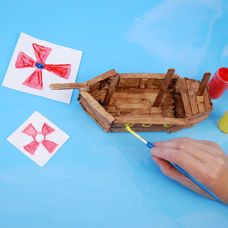 a child's hand is holding a paintbrush and painting the wooden boat