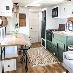 a kitchen and living room area in a mobile home with white walls, wood flooring and green cabinets