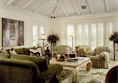 a living room filled with furniture and windows covered in white shuttered glass coverings