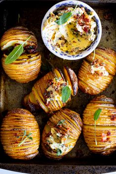 baked potatoes on a baking sheet with butter and herbs in the center, next to a bowl of dip