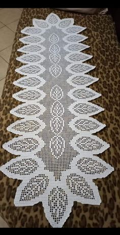 a white lace table runner on top of a leopard print floor mat with an intricate design