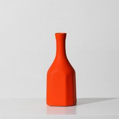 an orange vase sitting on top of a white table