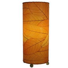 a lamp that is sitting on top of a wooden stand with a leaf design on it