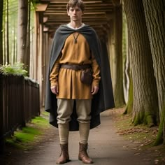 a young man dressed in medieval clothing standing on a path with trees lining the walkway