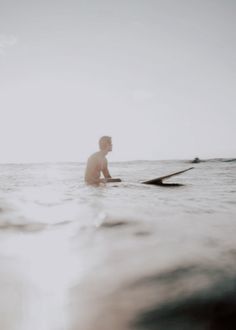 a man sitting on top of a surfboard in the ocean next to another person