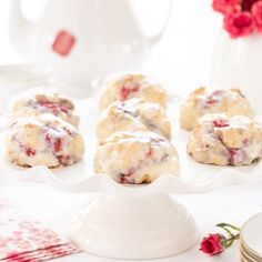 a white plate topped with cookies covered in icing next to cups and saucers