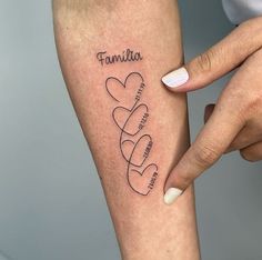 a woman's arm with two hearts on it and the word family written in cursive writing