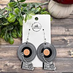 the earrings are black and white with an orange disc in the center, on top of a wooden table