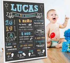 a baby sitting on the floor next to a birthday chalk board