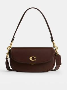 COACH Emmy 23 Glovetanned Leather Saddle Bag Size & Fit Dimensions: Height: 13.5cm x Width: 23cm x Depth: 5cm Handle drop: 21cm  Strap drop: 54cm Details Emmy 23 Glovetanned Leather Saddle Bag by Coach Brown  Small but mighty, the Emmy is a chic, compact saddle bag that's perfect for days where you only need your essentials - wear snug on the shoulder or style across the body for effortless hands-free appeal  Roomy enough to store your phone, keys, a lip balm and a small purse  Crafted from buttery soft glovetanned leather Signature C logo to the front  Flap closure with a clasp fastening  Includes a short removable handle and a detachable long shoulder strap for versatile styling Gold-tone metal hardware throughout  Internal slip and zip pockets Material & Care Coach Emmy Saddle Bag, Shoulder Bag Outfit, My Style Bags, Luxury Bags Collection, Dream Bag, Leather Saddle Bags, Dream Bags, Girly Bags, Bag Coach