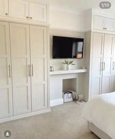 a bedroom with white closets and a flat screen tv on the wall above it