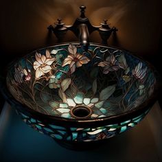 a glass bowl sink with flowers on the bottom and lights in the middle, along with two faucets