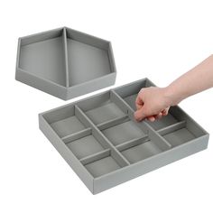 a person's hand is reaching for an empty tray in the shape of a hexagonal box