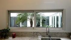 a kitchen sink sitting under a window next to a potted plant