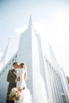 a bride and groom are kissing in front of the mormon temple at their wedding day