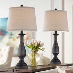 two lamps sitting on top of a table next to a vase with flowers in it