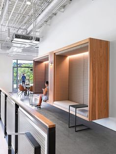 people are sitting at tables in an open space with white walls and wood paneling