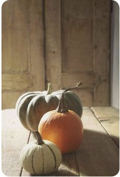 two small pumpkins sitting on top of a wooden table next to eachother