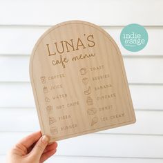 a person holding up a wooden sign that says luna's cafe menu