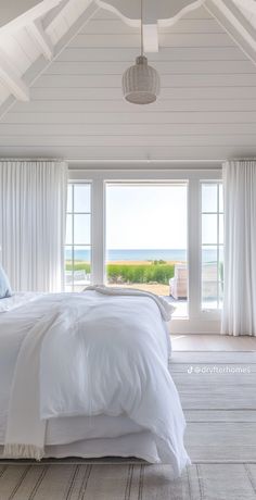 a white bed sitting in a bedroom next to two windows