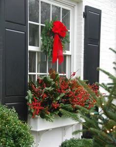 a christmas wreath on the window sill with red berries and greenery in it