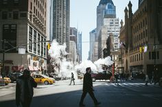 a man walking down the street with steam coming out of his mouth and buildings in the background