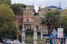 cars parked in front of an old building with palm trees on the side of the road