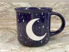 a blue coffee mug with a crescent and stars painted on the side, sitting on a marble countertop