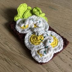 three crocheted flowers sitting on top of a wooden table