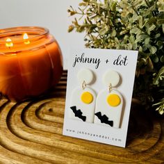 a pair of earrings sitting on top of a table next to a candle