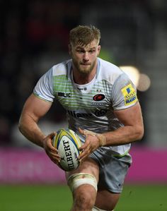 a man holding a rugby ball on top of a field