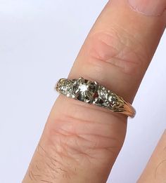 a woman's hand with a ring on it that has three stones in the middle