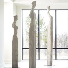 three sculptures are standing in front of a window