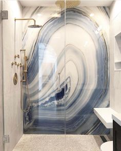 a white and blue marble bathroom with glass shower doors