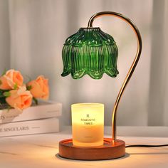 a green lamp sitting on top of a table next to a vase with flowers in it