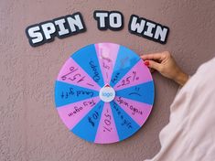 a pink and blue spin to win board with writing on the wall next to it